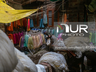 Farooq Ahmad arranges threads inside a dyeing center in Srinagar, Jammu and Kashmir, on December 16, 2024. Kashmiris dye fabric and threads...