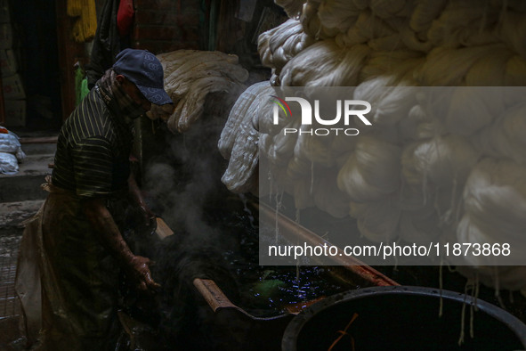 Farooq Ahmad washes threads inside a dyeing center in Srinagar, Jammu and Kashmir, on December 16, 2024. Kashmiris dye fabric and threads ma...