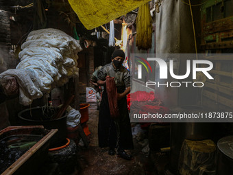 Waseem Khan carries threads inside a dyeing center in Srinagar, Jammu and Kashmir, on December 16, 2024. Kashmiris dye fabric and threads ma...