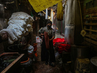 Waseem Khan carries threads inside a dyeing center in Srinagar, Jammu and Kashmir, on December 16, 2024. Kashmiris dye fabric and threads ma...