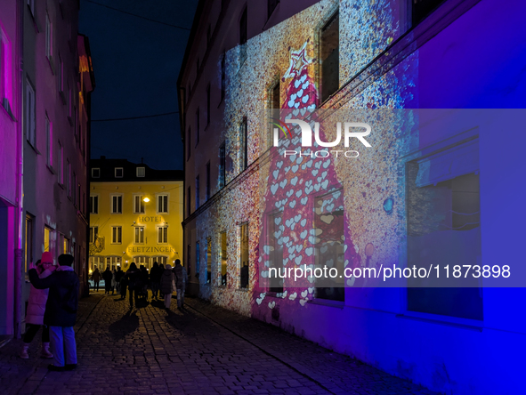 Historic buildings glow with colorful Christmas light projections in Wasserburg am Inn, Bavaria, Germany, on December 15, 2024. The historic...