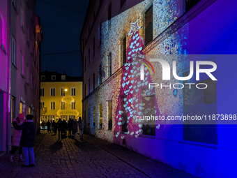 Historic buildings glow with colorful Christmas light projections in Wasserburg am Inn, Bavaria, Germany, on December 15, 2024. The historic...