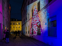 Historic buildings glow with colorful Christmas light projections in Wasserburg am Inn, Bavaria, Germany, on December 15, 2024. The historic...