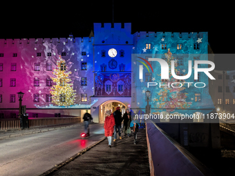 Historic buildings glow with colorful Christmas light projections in Wasserburg am Inn, Bavaria, Germany, on December 15, 2024. The historic...