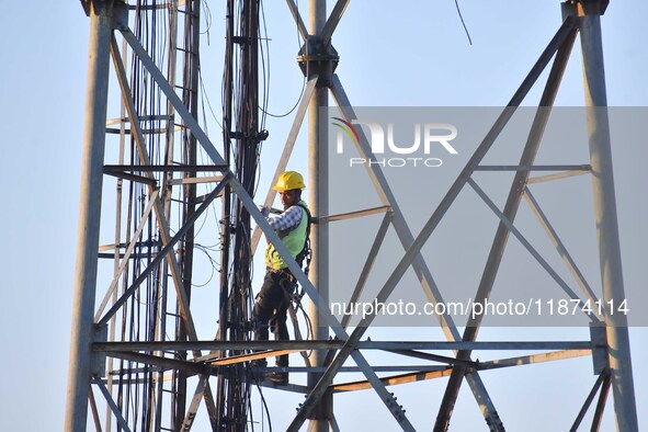 A telecom network engineer works on a mobile phone tower in Nagaon District, Assam, India, on December 16, 2024. 