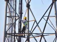 A telecom network engineer works on a mobile phone tower in Nagaon District, Assam, India, on December 16, 2024. (