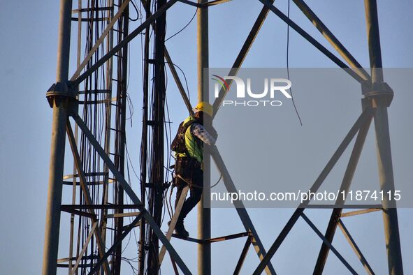 A telecom network engineer works on a mobile phone tower in Nagaon District, Assam, India, on December 16, 2024. 