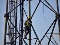 A telecom network engineer works on a mobile phone tower in Nagaon District, Assam, India, on December 16, 2024. (