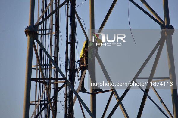 A telecom network engineer works on a mobile phone tower in Nagaon District, Assam, India, on December 16, 2024. 