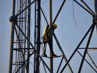 A telecom network engineer works on a mobile phone tower in Nagaon District, Assam, India, on December 16, 2024. (