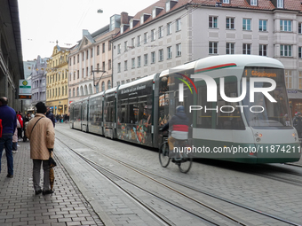 People are near a tram in Augsburg, Bavaria, Germany, on December 14, 2024. The Augsburg tramway is a vital part of the city's public transp...