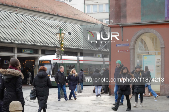 People are near a tram in Augsburg, Bavaria, Germany, on December 14, 2024. The Augsburg tramway is a vital part of the city's public transp...