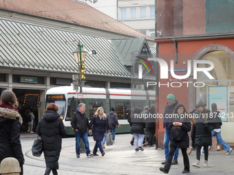 People are near a tram in Augsburg, Bavaria, Germany, on December 14, 2024. The Augsburg tramway is a vital part of the city's public transp...