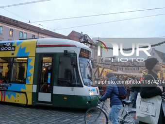 People are near a tram in Augsburg, Bavaria, Germany, on December 14, 2024. The Augsburg tramway is a vital part of the city's public transp...