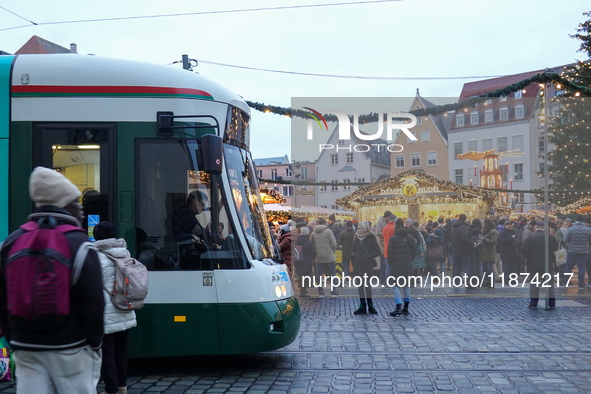 People are near a tram in Augsburg, Bavaria, Germany, on December 14, 2024. The Augsburg tramway is a vital part of the city's public transp...