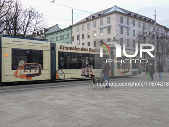 People are near a tram in Augsburg, Bavaria, Germany, on December 14, 2024. The Augsburg tramway is a vital part of the city's public transp...