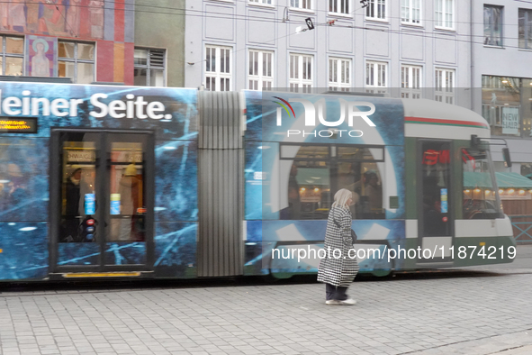 A woman passes a tram in Augsburg, Bavaria, Germany, on December 14, 2024. The Augsburg tramway is a vital part of the city's public transpo...