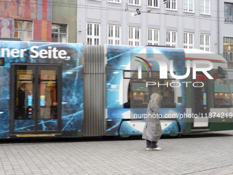 A woman passes a tram in Augsburg, Bavaria, Germany, on December 14, 2024. The Augsburg tramway is a vital part of the city's public transpo...