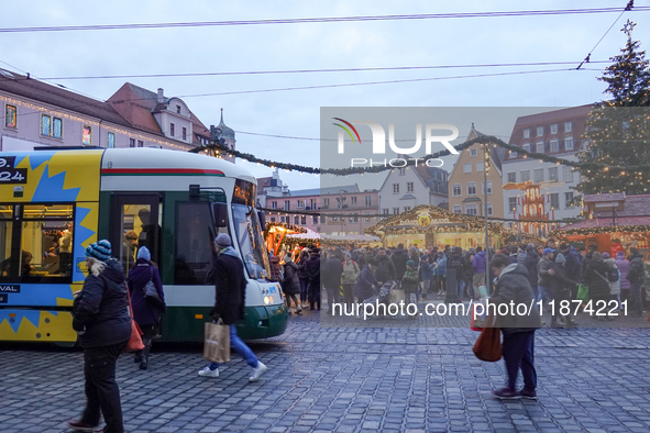 People are near a tram in Augsburg, Bavaria, Germany, on December 14, 2024. The Augsburg tramway is a vital part of the city's public transp...