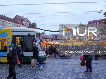 People are near a tram in Augsburg, Bavaria, Germany, on December 14, 2024. The Augsburg tramway is a vital part of the city's public transp...