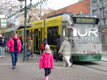 People are near a tram in Augsburg, Bavaria, Germany, on December 14, 2024. The Augsburg tramway is a vital part of the city's public transp...