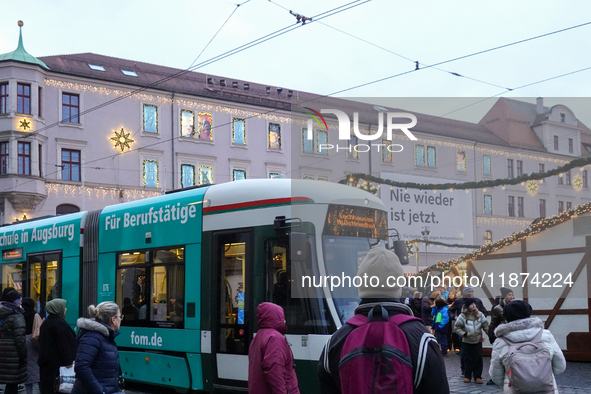 People are near a tram in Augsburg, Bavaria, Germany, on December 14, 2024. The Augsburg tramway is a vital part of the city's public transp...