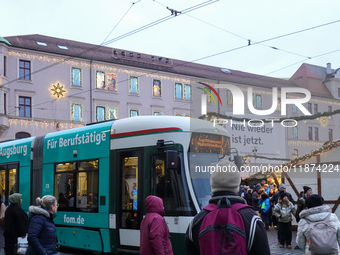 People are near a tram in Augsburg, Bavaria, Germany, on December 14, 2024. The Augsburg tramway is a vital part of the city's public transp...