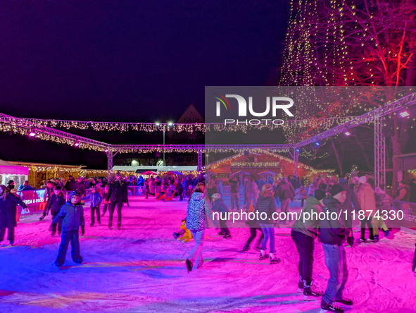 Families and people of all ages ice skate surrounded by vibrant lights and decorations in Wasserburg am Inn, Bavaria, Germany, on December 1...