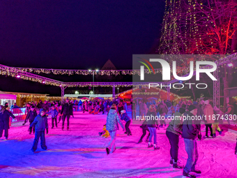 Families and people of all ages ice skate surrounded by vibrant lights and decorations in Wasserburg am Inn, Bavaria, Germany, on December 1...