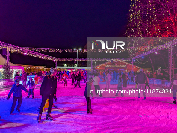 Families and people of all ages ice skate surrounded by vibrant lights and decorations in Wasserburg am Inn, Bavaria, Germany, on December 1...