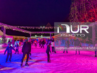 Families and people of all ages ice skate surrounded by vibrant lights and decorations in Wasserburg am Inn, Bavaria, Germany, on December 1...