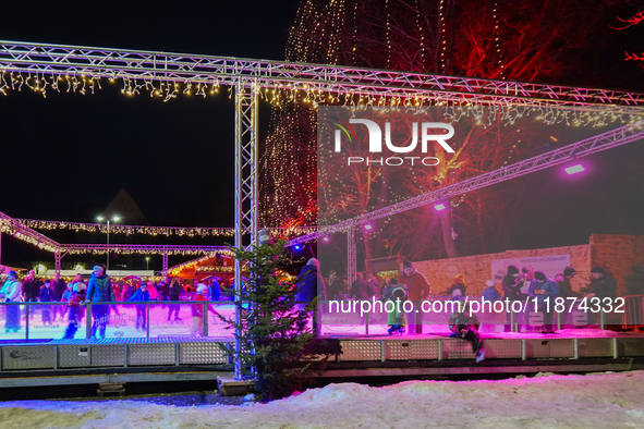 Families and people of all ages ice skate surrounded by vibrant lights and decorations in Wasserburg am Inn, Bavaria, Germany, on December 1...