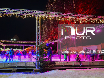 Families and people of all ages ice skate surrounded by vibrant lights and decorations in Wasserburg am Inn, Bavaria, Germany, on December 1...