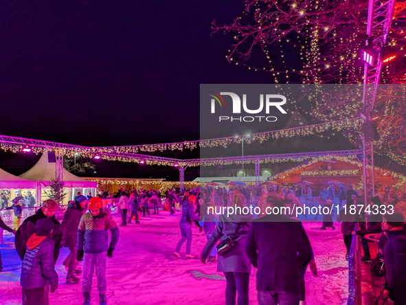 Families and people of all ages ice skate surrounded by vibrant lights and decorations in Wasserburg am Inn, Bavaria, Germany, on December 1...