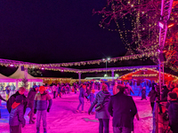 Families and people of all ages ice skate surrounded by vibrant lights and decorations in Wasserburg am Inn, Bavaria, Germany, on December 1...