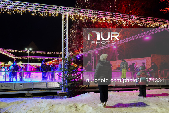 Families and people of all ages ice skate surrounded by vibrant lights and decorations in Wasserburg am Inn, Bavaria, Germany, on December 1...