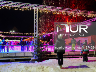 Families and people of all ages ice skate surrounded by vibrant lights and decorations in Wasserburg am Inn, Bavaria, Germany, on December 1...