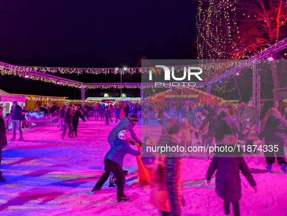 Families and people of all ages ice skate surrounded by vibrant lights and decorations in Wasserburg am Inn, Bavaria, Germany, on December 1...