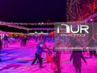 Families and people of all ages ice skate surrounded by vibrant lights and decorations in Wasserburg am Inn, Bavaria, Germany, on December 1...