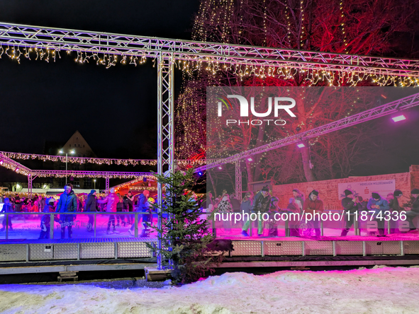 Families and people of all ages ice skate surrounded by vibrant lights and decorations in Wasserburg am Inn, Bavaria, Germany, on December 1...