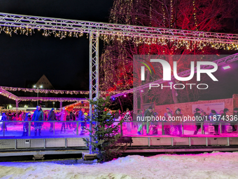 Families and people of all ages ice skate surrounded by vibrant lights and decorations in Wasserburg am Inn, Bavaria, Germany, on December 1...