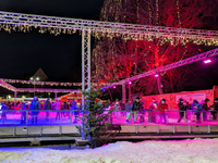 Families and people of all ages ice skate surrounded by vibrant lights and decorations in Wasserburg am Inn, Bavaria, Germany, on December 1...