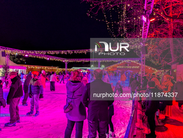 Families and people of all ages ice skate surrounded by vibrant lights and decorations in Wasserburg am Inn, Bavaria, Germany, on December 1...