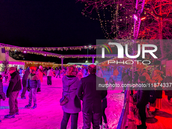 Families and people of all ages ice skate surrounded by vibrant lights and decorations in Wasserburg am Inn, Bavaria, Germany, on December 1...