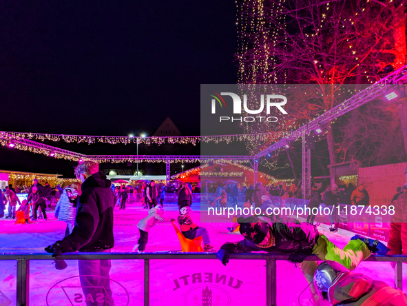 Families and people of all ages ice skate surrounded by vibrant lights and decorations in Wasserburg am Inn, Bavaria, Germany, on December 1...