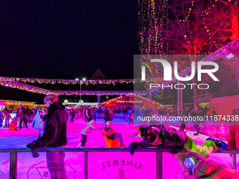 Families and people of all ages ice skate surrounded by vibrant lights and decorations in Wasserburg am Inn, Bavaria, Germany, on December 1...