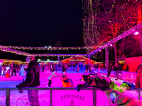 Families and people of all ages ice skate surrounded by vibrant lights and decorations in Wasserburg am Inn, Bavaria, Germany, on December 1...