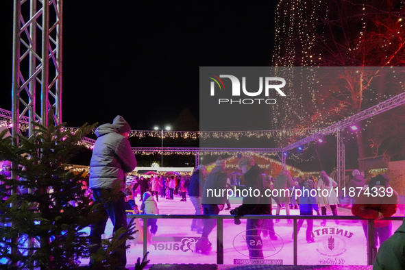 Families and people of all ages ice skate surrounded by vibrant lights and decorations in Wasserburg am Inn, Bavaria, Germany, on December 1...