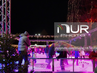 Families and people of all ages ice skate surrounded by vibrant lights and decorations in Wasserburg am Inn, Bavaria, Germany, on December 1...