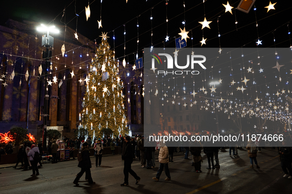 The main Christmas tree and New Year's illuminations are illuminated on Rustaveli Avenue as anti-government demonstrators gather outside the...